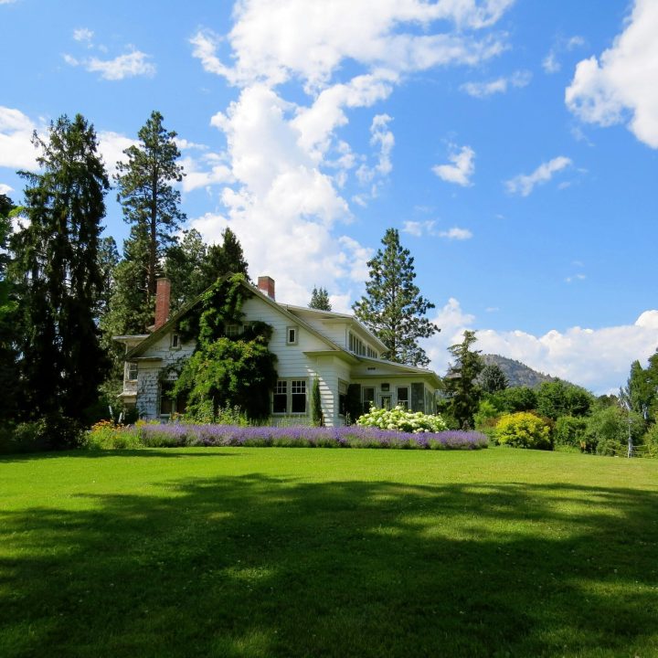 House Surrounded by Green Grass Below Clouds and Sky